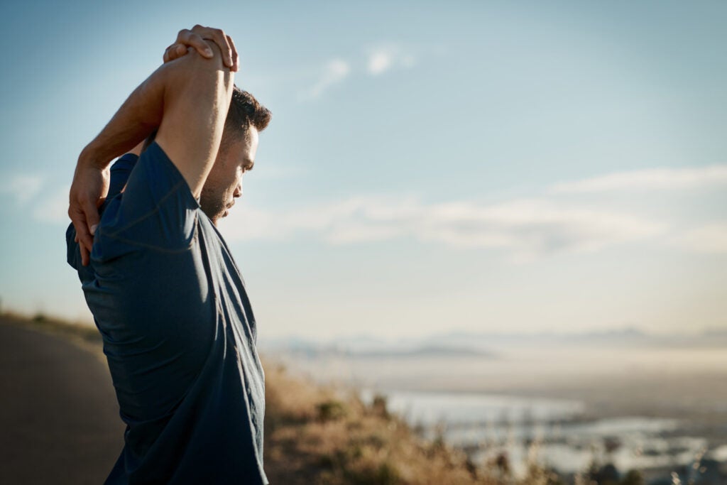 Cropped shot of a young man stretching his upper arms taking in the scenery before a workout